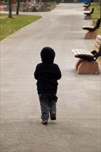 Child walking wooden park bench at a park