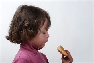 A young girl eating a bun