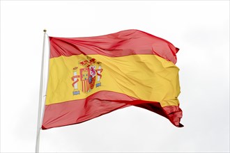 Flag of spain waving in the wind with cloudy sky in the background