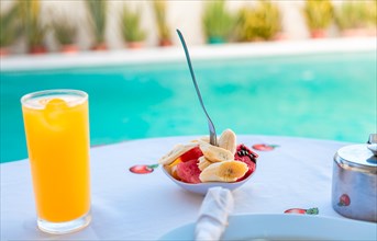 Breakfast fruit salad with swimming pool in the background. Fruit salad near the swimming pool