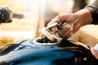 Hands opening the gas tank of the motorcycle with the key. Hand opening the gas tank of the motorcycle, Motorcyclist opening the gas tank of the motorcycle