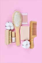 Eco friendly wooden beauty and hygiene products like comb and soap arranged on pink background