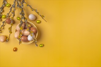 Palm catkin with Easter decoration, eggs, yellow background, copy room