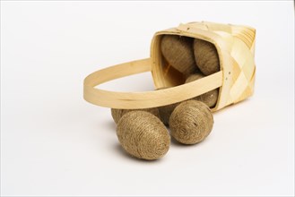 Easter composition. Basket with eggs wrapped in jute twine. White background. Studio