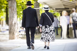 Elegant elderly couple in striking hats strolling through Baden-Baden, Baden-Wuerttemberg, Germany, Europe