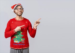 Cheerful christmas man concept pointing promo offer isolated, Friendly Christmas man pointing to a space to the side. Friendly smiling young man in christmas clothes pointing at a promo