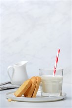 Rusk and glass of milk with drinking straw
