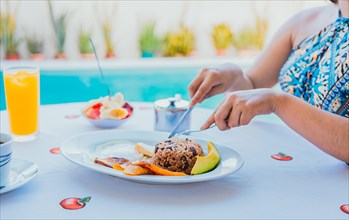 Breakfast near the swimming pool. hands of girl with a breakfast near the pool