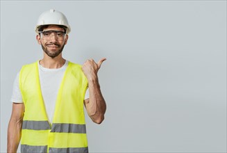 Portrait of engineer man pointing aside. Construction worker with vest pointing at an advertisement. Engineer man pointing to side. Builder engineer pointing finger to the right isolated