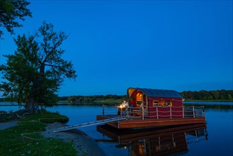 Man sitting in the blue hour on a houseboat, house raft, in front of the island Kiehnwerder, Breitlingsee, Brandenburg an der Havel, Havelland, Brandenburg, Germany, Europe