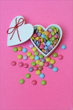 Chocolate lentils in heart-shaped container, Smartie