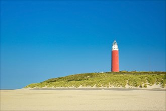 Lighthouse at northern beach of island Texel in Netherlands on summer day with blue sky