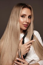 Beautiful blond girl with a perfectly hair, and classic make-up with a strand of hair for extension. Beauty face and hair. Picture taken in the studio
