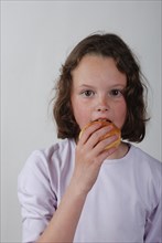 A young girl eating a bun