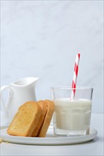 Rusk and glass of milk with drinking straw