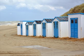 Row of white and blue beach sheds on the beach of Texel in the Netherlands