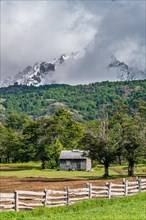 Shingle-roofed wooden house in front of snow-capped mountains, Villa Cerro Castillo, Cerro Castillo National Park, Aysen, Patagonia, Chile, South America