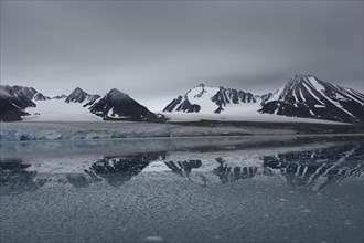 Lilliehook Glacier, Lilliehoeoekbreen, glaciated mountain peaks behind, with water reflection, in front ice chunks in the water, Lilliehook Fjord, Spitsbergen