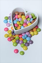 Chocolate lentils in heart-shaped container, Smartie