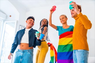 LGBT pride, lgbt rainbow flag, group of friends dancing and toasting with glasses in a house at party