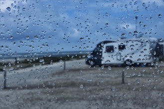View through a window with raindrops on a camper van on a camper van pitch by the sea, Portbail, Normandy, France, Europe