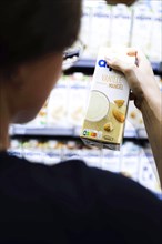 Younger woman buys vanilla almond milk in the supermarket. Radevormwald, Germany, Europe