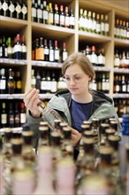 Young woman, student buys alcoholic drinks at the supermarket. Radevormwald, Germany, Europe