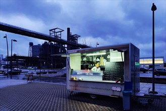 Outside snack bar in front of the Phoenix West blast furnace at dusk, Dortmund, Ruhr area, North Rhine-Westphalia, Germany, Europe