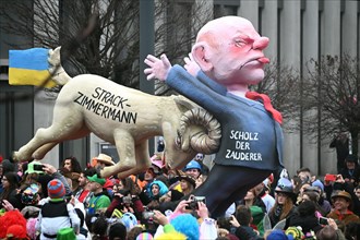 Theme float by Jaques Tilly: Federal Chancellor Olaf Scholz the procrastinator, attacked during a Strack-Zimmermann buck, Rosenmontagszug in Duesseldorf, North Rhine-Westphalia