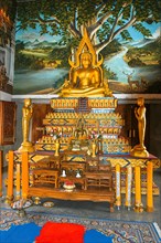 Gilded gold-coloured Buddhist altar with statue of seated Buddha in background mural with deer, Buddhist temple Wat Sri Sunthon, Thalang, Phuket Island, Thailand, Asia