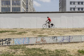A cyclist at the Berlin Wall stands out at the East Side Gallery in Berlin, 26.06.2022., Berlin, Germany, Europe