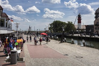 Seaside resort Buesum, pedestrian zone at the museum harbour with lighthouse in the background, Buesum, Schleswig-Holstein, Germany, Europe
