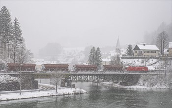 OeBB goods train loaded with ore and the electric locomotive Taurus on the drawbridge over the river Enns in the snowy landscape of Reichraming, Upper Austria, Austria, Europe