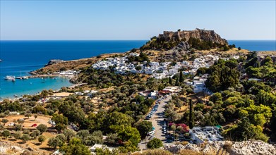 View of Lindos with white houses, acropolis and beach, Rhodes, Greece, Europe