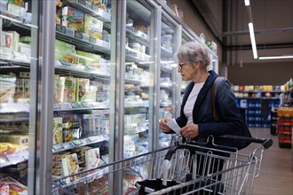 Elderly woman shopping in supermarket. Radevormwald, Germany, Europe