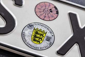 Official seal of the federal state of Baden-Wuerttemberg on a motor vehicle registration plate, TUeV badge and state coat of arms, Stuttgart, Baden-Wuerttemberg, Germany, Europe