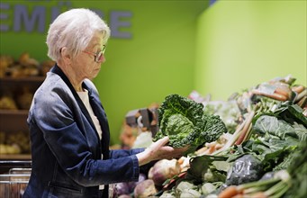 Elderly woman buys a savoy cabbage in the supermarket, Radevormwald, Germany, Europe
