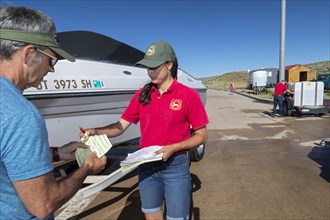 Evanston, Wyoming, An employee of the Wyoming Game & Fish Department gives a boat owner a receipt after inspecting and decontaminating the watercraft at a mandatory inspection station along the Utah b...