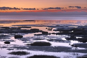 Evening landscape shortly after sunset with draining water in the Wadden Sea National Park. The Wadden Sea off the North Frisian coast is a UNESCO World Heritage Site. Dike at Strandweg, Friedrichskoo...