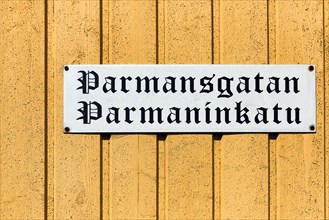 Bilingual street sign on yellow wooden facade, old wooden house, street name Parmansgatan in Swedish and Finnish, Old Town of Kristinestad, Kristiinankaupunki, Oesterbotten, Finland, Europe