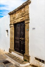 Old wooden doors with pebble mosaics on the floor, winding streets with white houses, Lindos, Rhodes, Greece, Europe