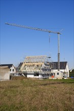 Residential house with scaffolding and open roof truss, construction site in a new housing estate, Kamen, North Rhine-Westphalia, Germany, Europe