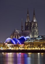 City panorama with only dimly lit Cologne Cathedral and the Rhine at night, Cologne, Rhineland, North Rhine-Westphalia, Germany, Europe