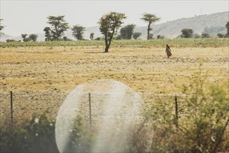 A woman walks across an arid field, photographed in Addis Ababa, 12.01.2023., Addis Ababa, Ethiopia, Africa
