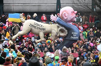 Theme float by Jaques Tilly: Federal Chancellor Olaf Scholz the procrastinator, attacked during a Strack-Zimmermann buck, Rosenmontagszug in Duesseldorf, North Rhine-Westphalia