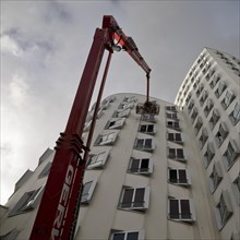 Building cleaner on a working platform with extended crane at Gehry Bau Neue Zollhof 3, Duesseldorf, North Rhine-Westphalia, Germany, Europe