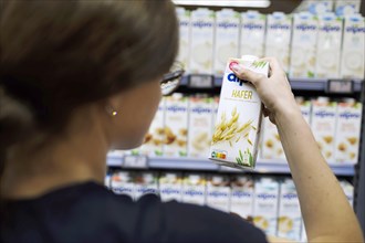 Young woman buys oat milk at the supermarket. Radevormwald, Germany, Europe