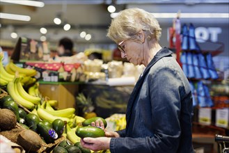 Older woman buys avocados at the supermarket. Radevormwald, Germany, Europe
