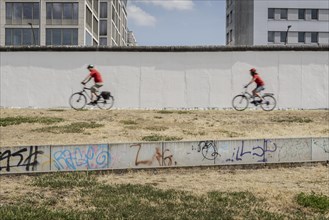 Two cyclists at the Berlin Wall stand out at the East Side Gallery in Berlin, 26.06.2022., Berlin, Germany, Europe