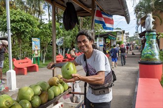 Tortuguero, Costa Rica, A street vendor cuts open a green coconut for a tourist in this small village on the Caribbean coast. The refreshing coconut water inside this then sipped through a straw, Cent...